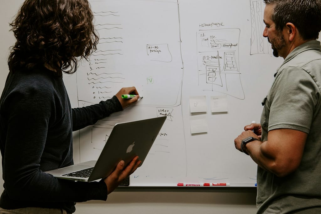 Web designers planning a website wireframe on a whiteboard